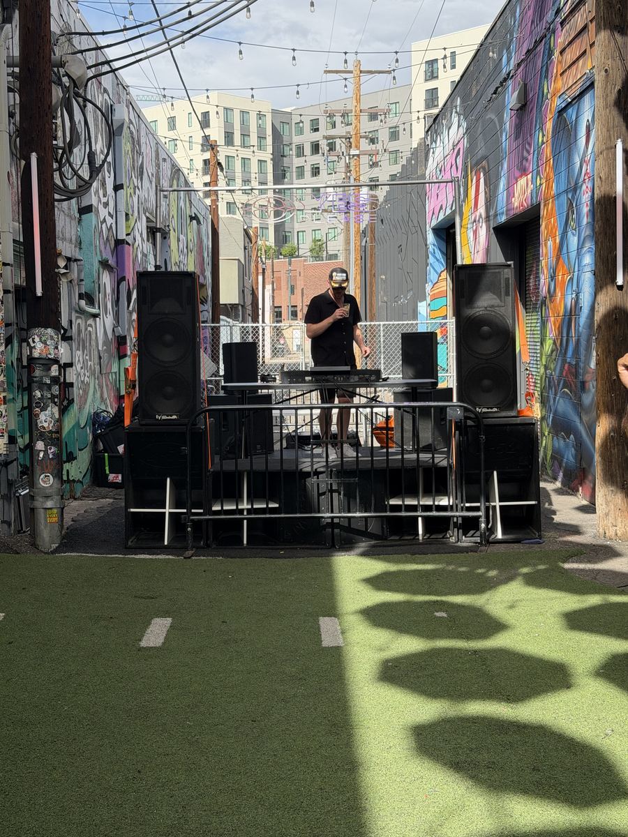 A DJ playing a daytime set on Harambe in the alley at Tracks Denver